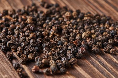 Siyah biberler eski ahşap arka plana saçılmış..