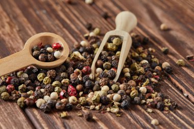 Çok renkli biberler ahşap spatula ve kaşıkla karıştırıldığında eski ahşap zemin üzerine saçılmıştır..