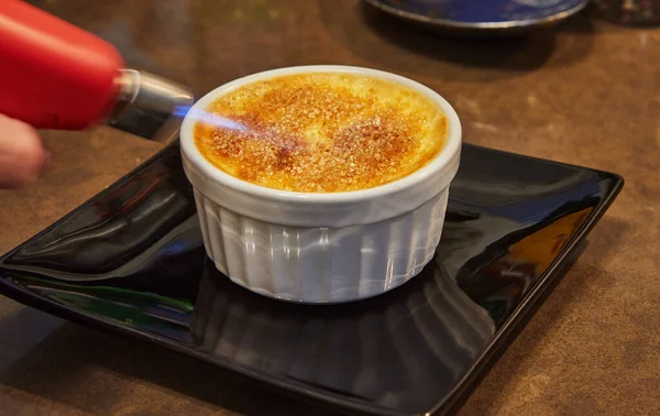 Creme brulee with mushrooms in special form, the chef burns sugar with burner. French gourmet cuisine.