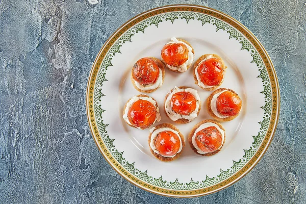 Svačinky se sýrem ricotta a cherry rajčaty na bílém vinném talíři. Francouzská gurmánská kuchyně — Stock fotografie