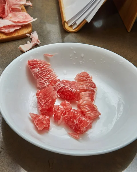 Czerwone plasterki pomelo leżą na talerzu gotowym do gotowania — Zdjęcie stockowe