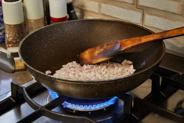 As cebolas roxas fritam-se em uma panela de ato de fritar em um fogão a gás. Prepare ingredientes e legumes antes de cozinhar — Fotografia de Stock