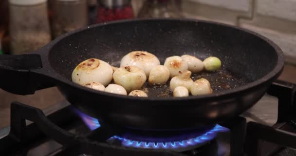 Sjalotten worden gebakken in pan op gasfornuis — Stockvideo