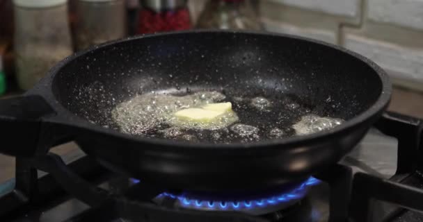 Boter in de koekenpan, in stukjes gesneden champignons gieten. Gasfornuis — Stockvideo