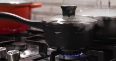 Gaz ocağının üstünde kapağı olan tencere kapağı kapağının altından buhar çıkıyor.