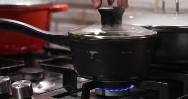 Garnek z pokrywką na ognisku kuchenki gazowej zdejmuje pokrywę i wychodzi para — Wideo stockowe