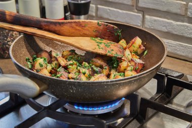 Kızarmış patatesli tava, maydanoz ve gaz sobasında ahşap spatulalar. Adım adım tarif.