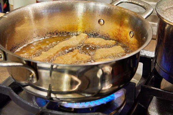 Bugnes, French donuts in boiling oil in saucepan — стоковое фото