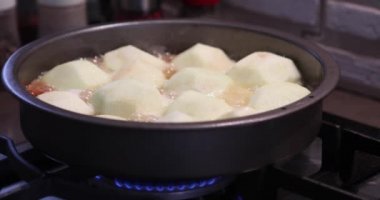 Apples boiling in a frying pan on a gas stove. Cooking apple tart tatin