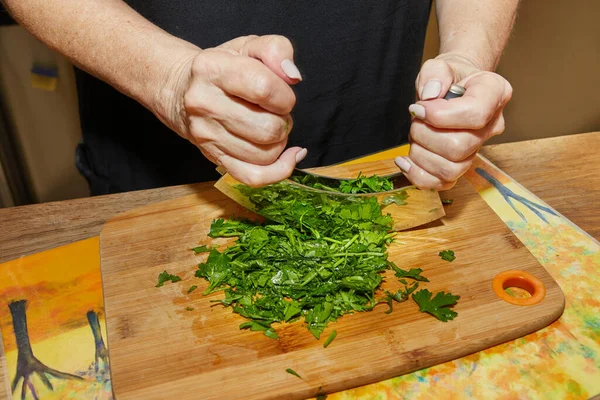 Şef maydanozu özel bir aletle doğruyor, mezzaluna, iki bıçakla, bu da işi hızlandırıyor..