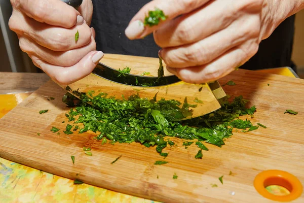Şef maydanozu özel bir aletle doğruyor, mezzaluna, iki bıçakla, bu da işi hızlandırıyor..