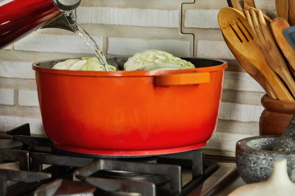 Şef haşlanmış pırasa, lahana, turp, havuç ve soğan tenceresine su döker..