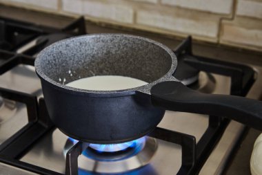 Krema, keki yapmak için gaz sobasında tencerede pişirilir..