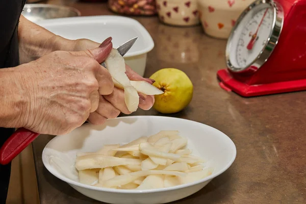 Chef cuts the pears into slices for chocolate cake with pear and nuts. Step by step recipe.