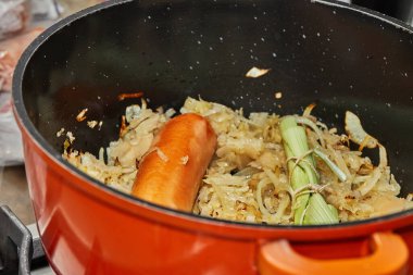 Alsatian lahana turşusu yapmak için yeşil buketli bir tencerede füme sosis ve lahana..