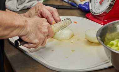 Şef evdeki mutfakta soğanı dilimlere ayırıyor..