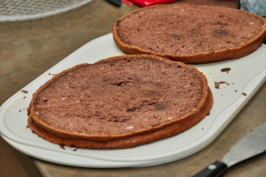 Şef armut ve cevizli turta yapmak için çikolatalı keki ikiye böler..