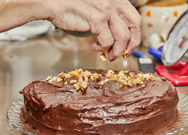 Chef sprinkles walnuts on the cake to make chocolate cake with pears and walnuts.