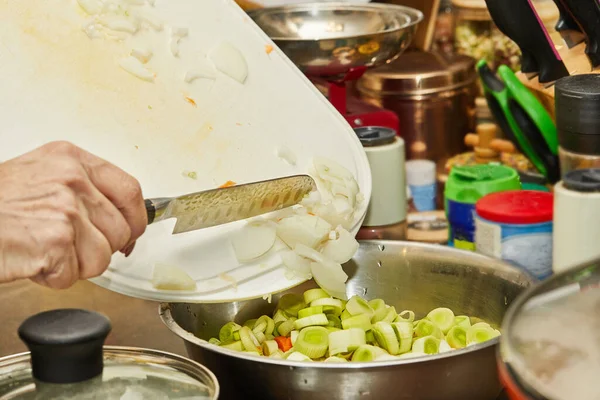 Şef doğranmış soğanı pırasa ve havuç kasesine atar..