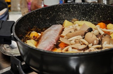 Havuç, mantar ve patatesle pişirilmiş balık, sebzeli palmiye balığı güveci yapmak için gaz sobasında tavada kızartılır. Adım adım tarif.