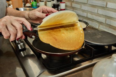Chef pan-frying Crepe Suzette pancakes with cognac and citrus sauce.