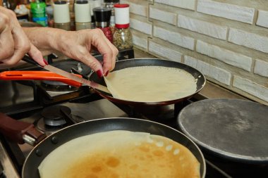Chef pan-frying Crepe Suzette pancakes with cognac and citrus sauce.