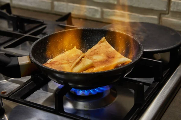 Chef pan-frying Crepe Suzette pancakes with cognac and citrus sauce. Flombe French gourmet cuisine.