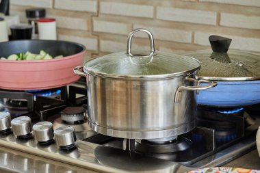 Pots with cooking food in the kitchen on gas stove.