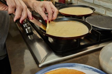 Chef pan-frying Crepe Suzette pancakes with cognac and citrus sauce.