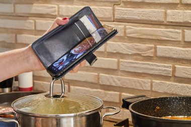 Chef shoots video on mobile phone, preparing meat.