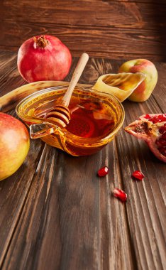 Rosh hashanah - jewish new year holiday concept. Bowl in the shape of an apple with honey, apples, pomegranates, shofar on wooden vintage background. Copy space
