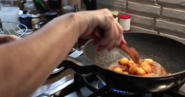 Şef kavrulmuş karamelli sosla kavrulmuş kavunları gaz ocağında tavada pişiriyor..