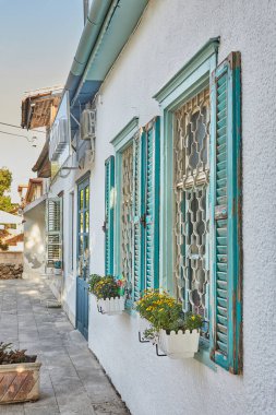 Ahşap pencereler ve kepenkler gün batımında maviye boyanmış..