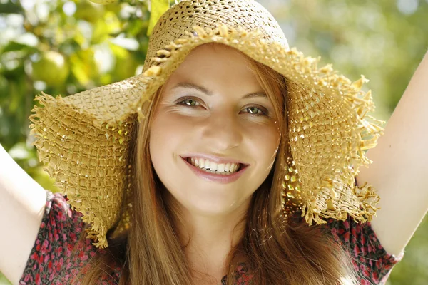 Giovane donna felice in giardino con cappello di paglia — Foto Stock