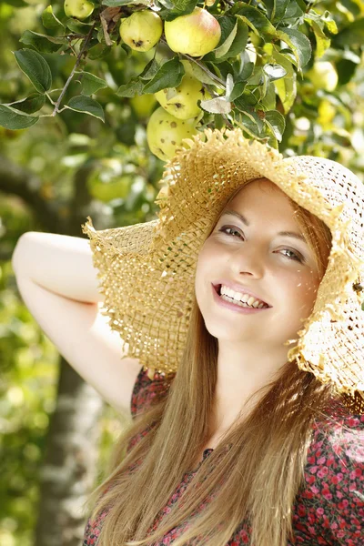 Happy young woman in the garden with straw hat — Stock Photo, Image