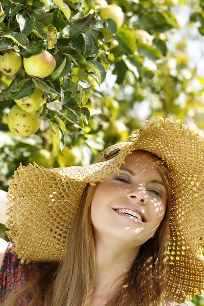 Gelukkig jonge vrouw in de tuin met stro hoed — Stockfoto