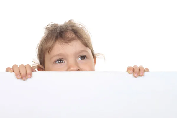 Schattig klein meisje kijkt over een witte muur — Stockfoto