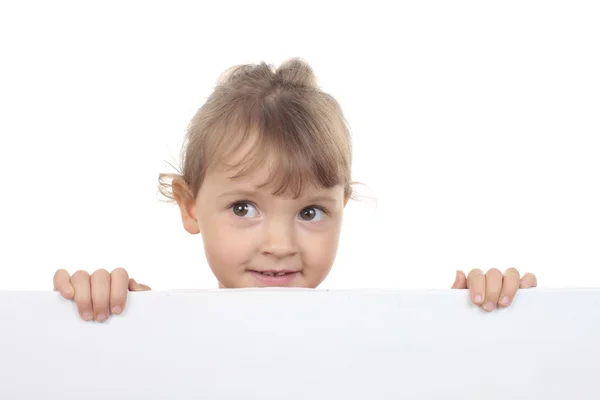 Schattig klein meisje kijkt over een witte muur — Stockfoto