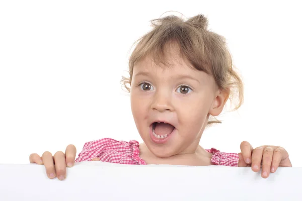 Schattig klein meisje kijkt over een witte muur — Stockfoto