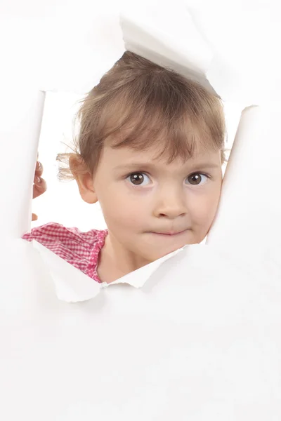 Menina olha através de uma parede de papel branco — Fotografia de Stock