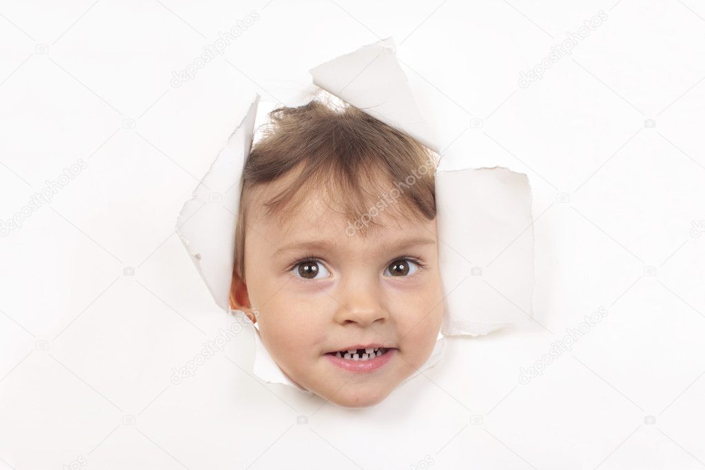 Little girl looks through a white paper wall