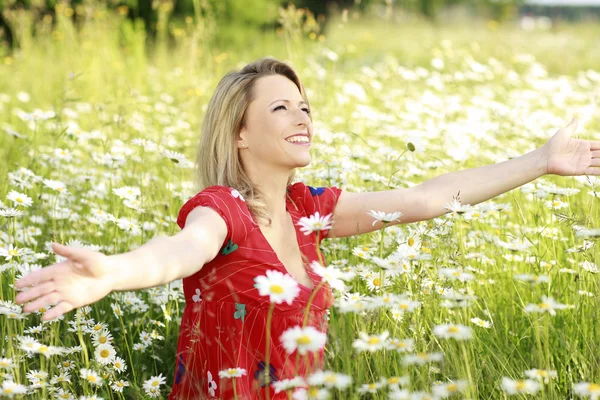 Счастливая женщина с распростертыми руками на цветочном поле — стоковое фото