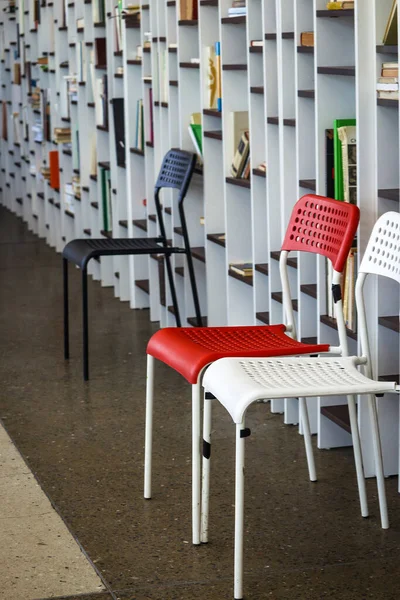 Tre plaststolar står nära hyllor med böcker i biblioteket — Stockfoto