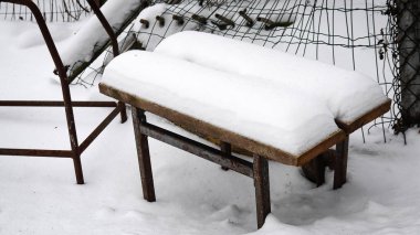 Snow layer on double bench standing in a winter yard