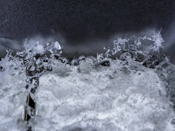 層と氷の表面 雪片と黒ガラスの背景マクロショット上の大きな亀裂 — ストック写真