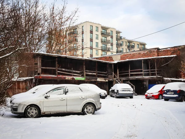 Gammal väderkvarn skjul på modern nybyggd byggnad och parkering med bilar på vintern — Stockfoto