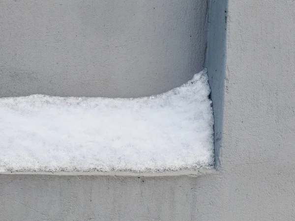 Schneeschicht klebt an Betoneinbuchtung in grauer Kaltwand — Stockfoto