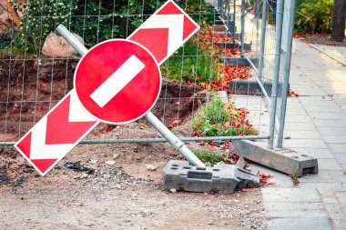 İnşaat alanı ve beton yol kenarındaki yere düşen kırmızı ok işaretinde kırmızı dur işareti