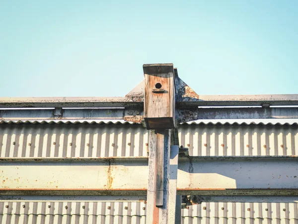 蓝天背景下春天钢墙建筑上的鸟屋 — 图库照片