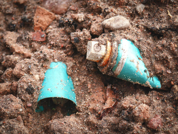 Металл синий дезодорант спрей бутылку оставляют в качестве мусора на лесной земле в мокрый песок и камни с пластиковой чашкой лежащих рядом. Пример опасных отходов в природной среде.